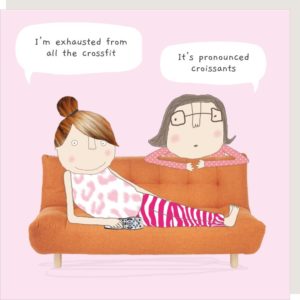 Crossfit greetings card. A lady reclining on a sofa holding a TV remote. Another lady is leaning over the back of the sofa. Speech bubble captions: "I'm exhausted from all the crossfit"... "It's pronounced croissants."
