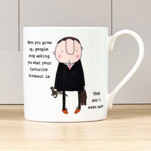 white coffee mug with an image of a man dressed in a suit, holding a briefcase and a toy dinosaur, caption reads 'when you grow up, people stop asking you what your favourite dinosaur is. They don't even care'.